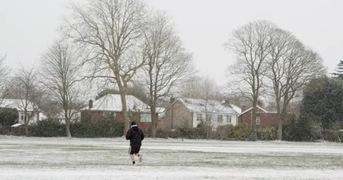 A man dressed in winter clothes jogging with his back to camera in a big park Stock Footage 148267923