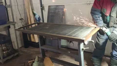 A man is dressed in work clothes in his workshop is grinding a metal product Stock Footage 149384419