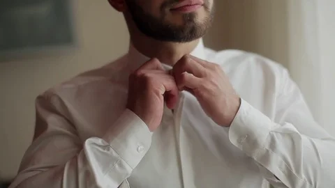 Man dresses buttoning shirt collar and puts hand in pocket close up no face Stock Footage 72597558
