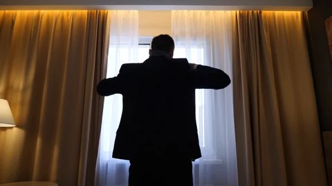 A man is dressing a jacket near a window Stock Footage 91425776