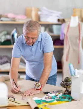 Man dressmaker drawing pattern on paper in workshop 库存照片