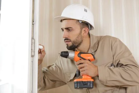 Man drilling a hole in a window frame Stock Photos