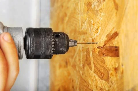 A man drills a drill into an osb panel Stock Photos