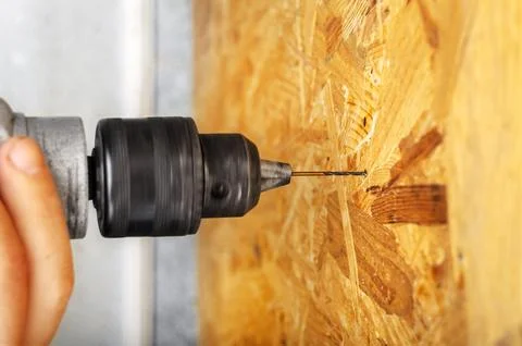 A man drills a drill into an osb panel Stock Photos
