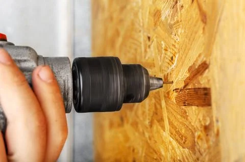 A man drills a drill into an osb panel Stock Photos