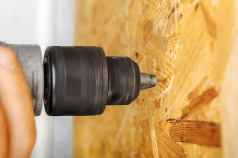 A man drills a drill into an osb panel Stock Photos