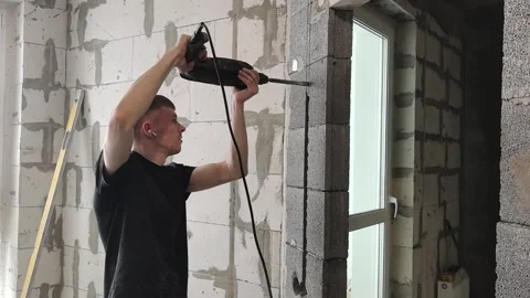 Man drills wall to install door frame in home renovation project in living room Vídeo Stock 328439373