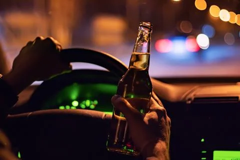 Man drink beer while driving at night in the city. Dangerously driving Stock-Fotos