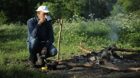 Man drink cup of tea nea campfire Stock Footage 64048897