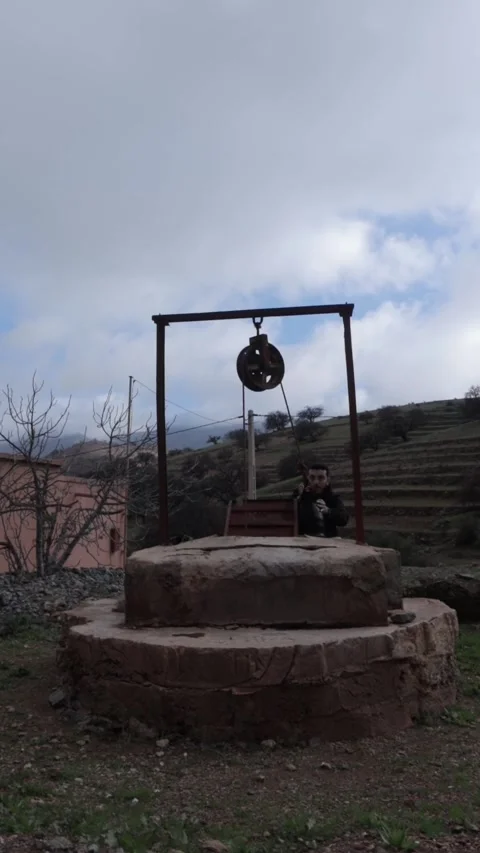 Man Drinking and Resting at Ancient Stone Well Berber Village Morocco Stock Footage 332769337