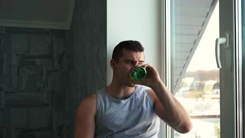 Man drinking beer and bottles sitting by the window Stock Footage 143994691
