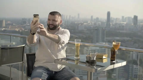 Man drinking beer and doing selfies on the rooftop Stock Footage 90557445