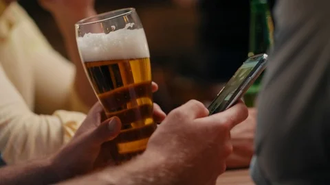 Man drinking beer and using mobile phone in the pub Stockbeeldmateriaal 108309752