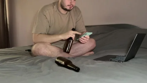 Man Drinking Beer and Using Phone in Dim Room Stock Footage 310511293