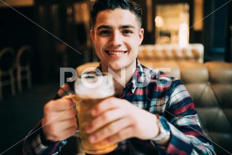Man drinking beer. Handsome young man drinking beer while sitting at the bar Stock Photos
