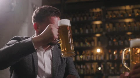 A man is drinking beer in a pub and talking with a friend, listening attentively Stock Footage 278471529