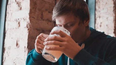 A man is drinking beer at a table in a cafe Stock Footage 87285489