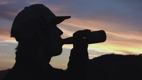 Man Drinking From Bottle At Sunset In Mountains Stock Footage 139371118