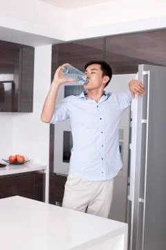 Man drinking a bottle of water in the kitchen Foto stock