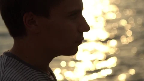 Man drinking bottle of wine during sunset near sea, slow motion Stock Footage