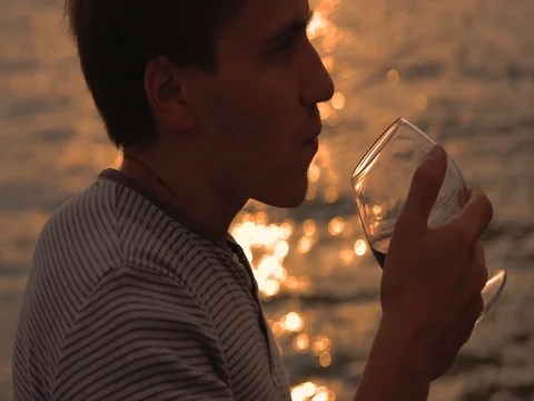 Man drinking bottle of wine during sunset near sea Stock Footage 80599175