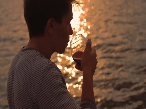 Man drinking bottle of wine during sunset near sea Stock Footage 80599252