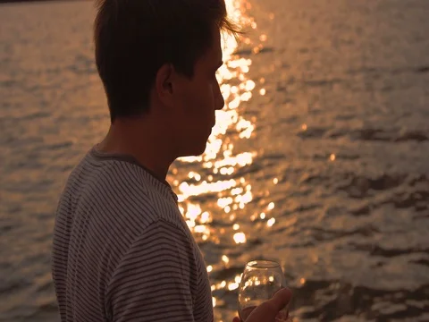 Man drinking bottle of wine during sunset near sea Stock Footage 80599289