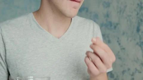 Man drinking capsule with omega 3, vitamin D with glass of water. Nutritional Stock Footage 270571144