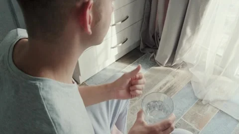 Man drinking capsule with omega 3, vitamin D with glass of water sitting on a Video stock 270571566