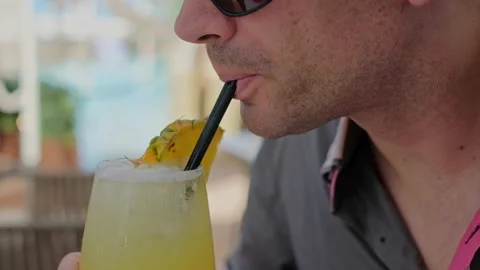 Man is drinking a cocktail. Close up of a face with glass and a straw. Video stock 197696253
