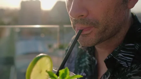 Man is drinking a cocktail. Close up of a face with glass and a straw. Video stock 200255580