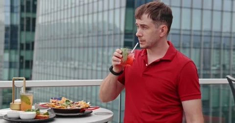 Man Drinking Cocktail at Rooftop Bar City Skyline Background Видео 329562892