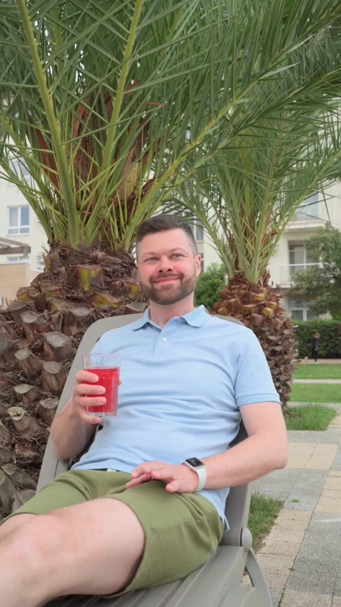 Man drinking cocktail while relaxing on beach bed Stock Footage 275331827