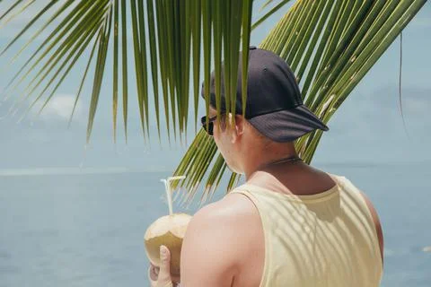 Man drinking coconut on the tropical beach at summer day Stock Photos