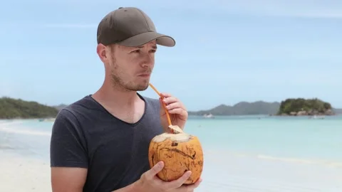 Man drinking coconut on white sand beach Stock Footage 160757969