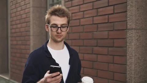 Man drinking coffee and net surfing while walking in the street 스톡 동영상 98309110