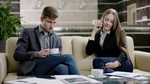 Man drinking coffee and taking phone from woman in hall Stock Footage 74280490