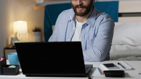 Man is drinking coffee and talking on video connection at home. Bearded guy in Stock Footage 129374771