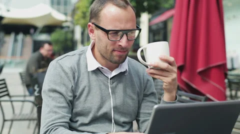Man drinking coffee and using laptop in street cafe, steadycam shot 스톡 동영상 37128686