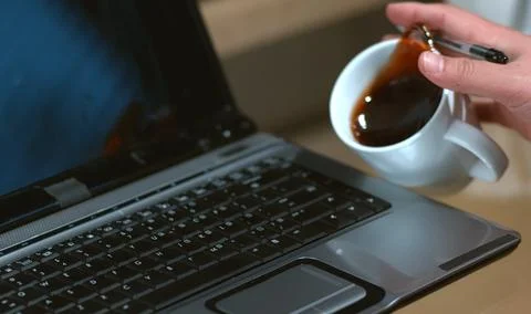 A man is drinking coffee and using laptop computer Stock Photos