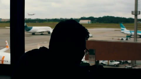 Man drinking coffee and waiting at the airport while an airplane take off Stock Footage 148699054