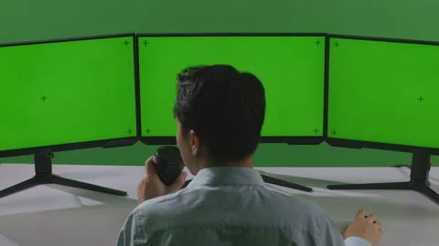 Man Drinking Coffee And Working With Mock Up Multiple Computer Monitor In Green Stock Footage 249633881