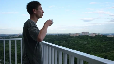 Man drinking coffee on balcony. enjoying time staying at home Stock Footage 312326835
