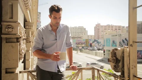 Man drinking coffee on balcony 스톡 동영상 76734576