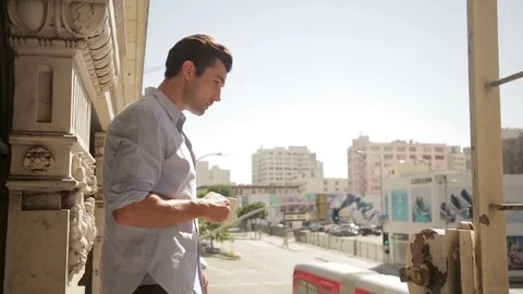 Man drinking coffee on balcony 스톡 동영상 76734631