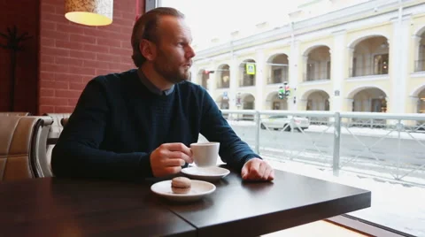 Man drinking coffee in a city cafe near window and waiting for someone Stock Footage 67674023
