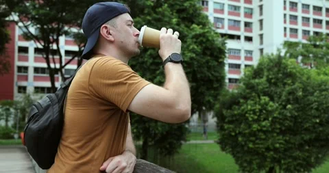 Man Drinking Coffee from Disposable Cup in Urban Park Video stock 333464408