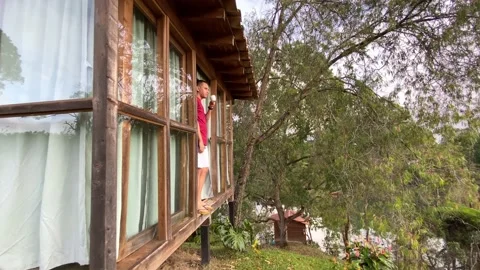 Man drinking coffee from a hostel. Man relaxing at a travel destination Stock Footage 230978417