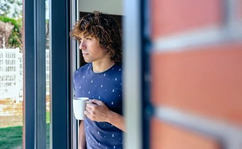 Man drinking coffee leaning against the window frame Stock Photos