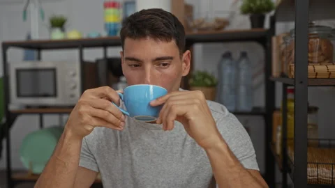 Man drinking coffee in office kitchen surrounded by plants, microwave, and .. Stock Footage 306382826